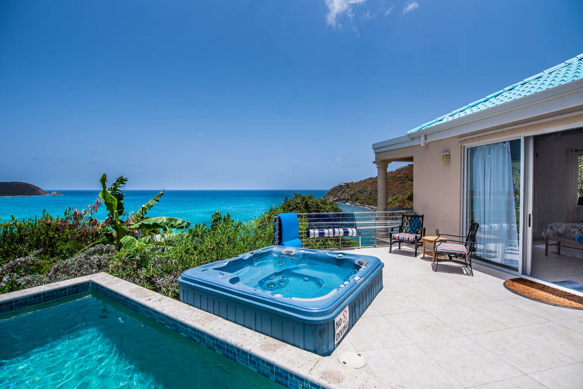 Hot tub and plunge pool on the tiled deck with panoramic turquoise sea views