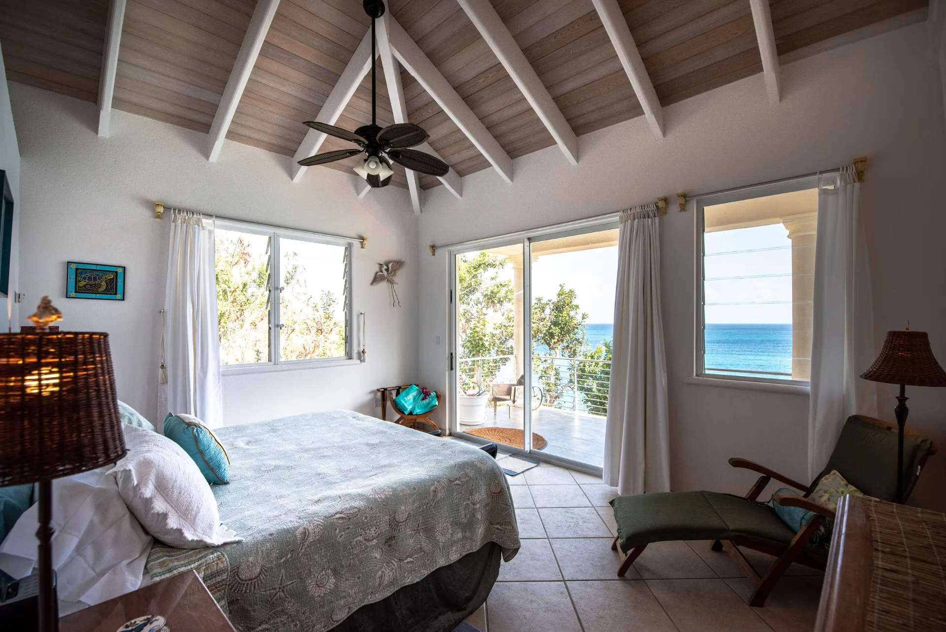 Master suite from the doorway, showing the king bed, chaise lounge and ocean views through every window