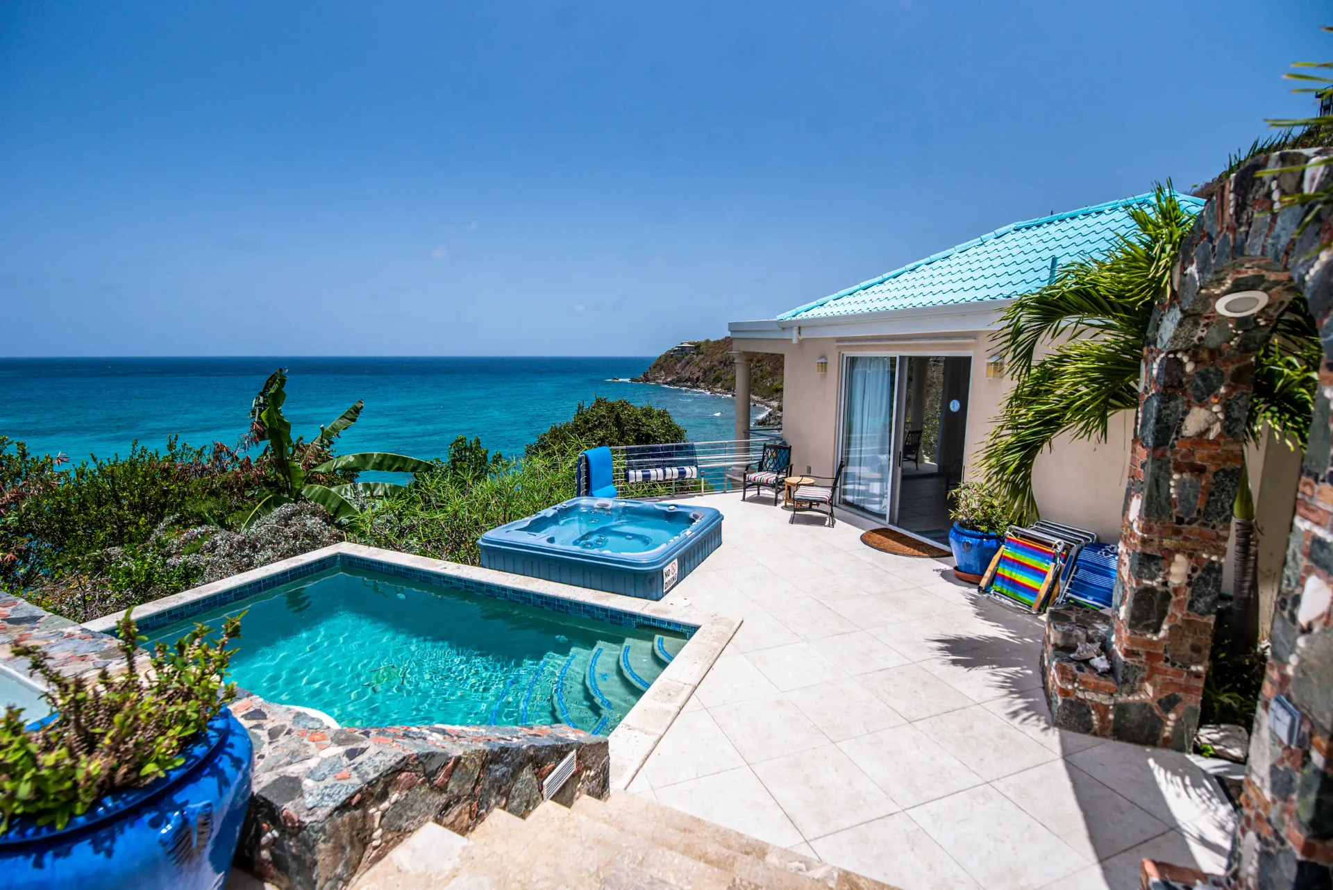 Hot tub and pool overlooking the sea with the guest cottage behind