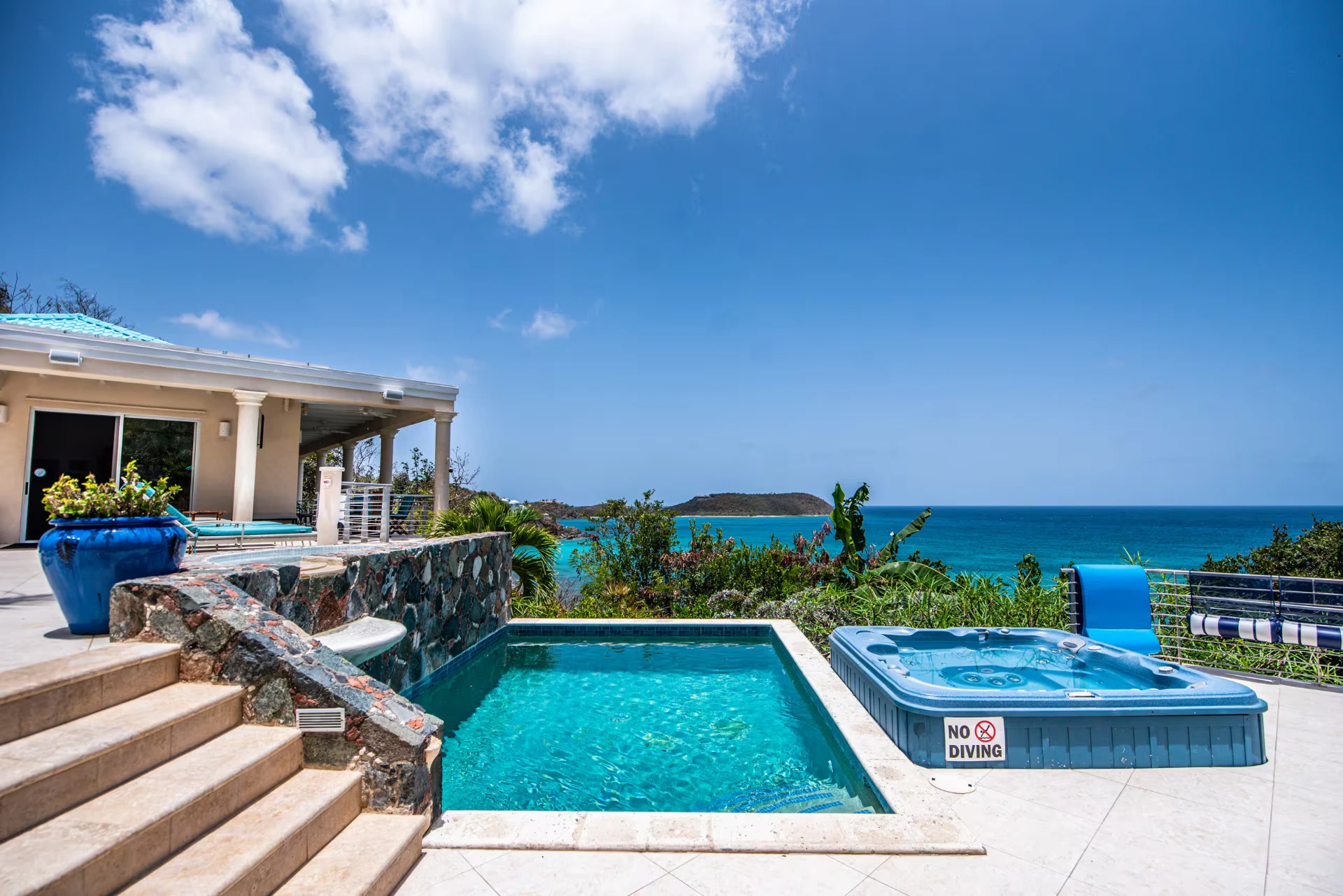 Pool and hot tub on the tiled deck with open ocean views