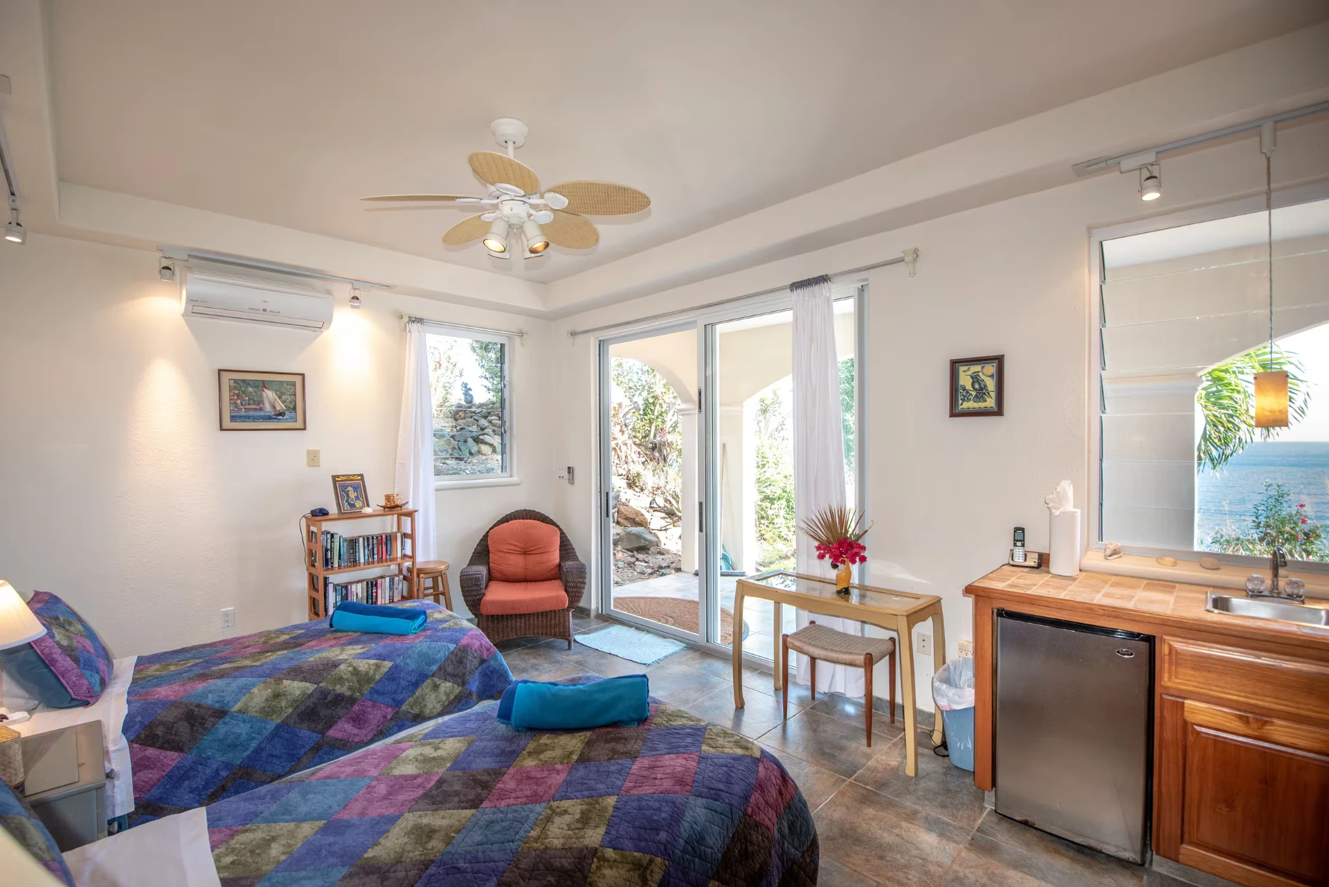 Downstairs guest suite with two twin beds, ceiling fan, wet bar and sliding doors to a garden patio with sea views