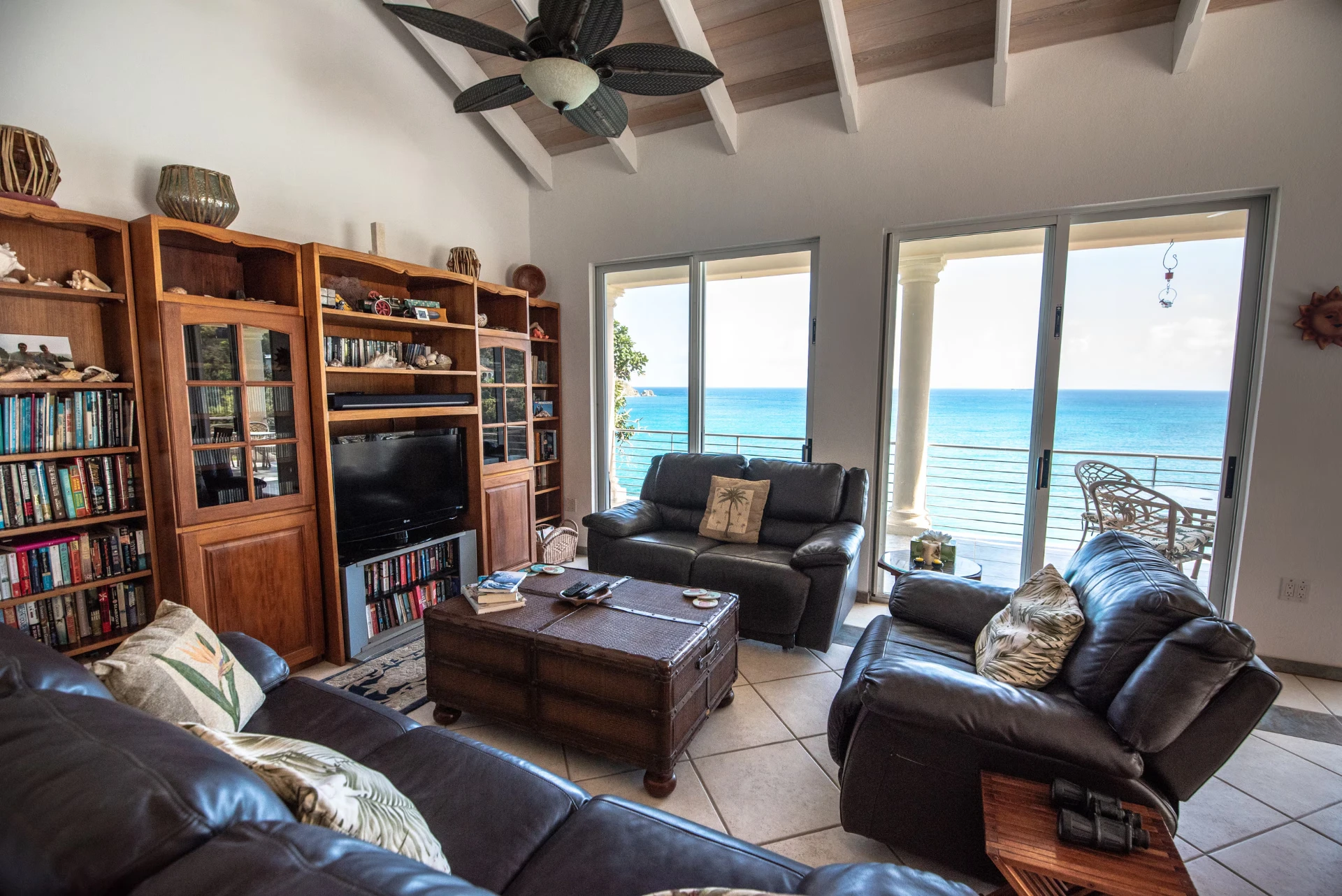 Leather seating, bookshelves and a wall of sliding doors overlooking the ocean