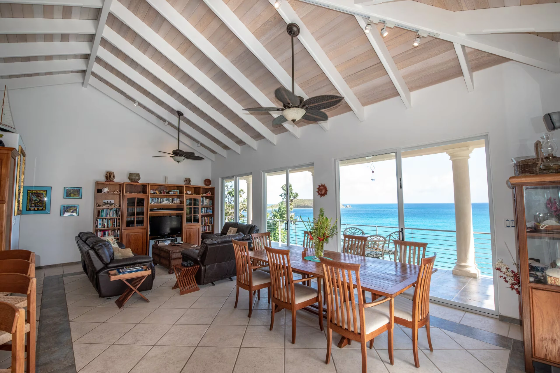 Dining table for eight beside sliding doors framing the turquoise bay