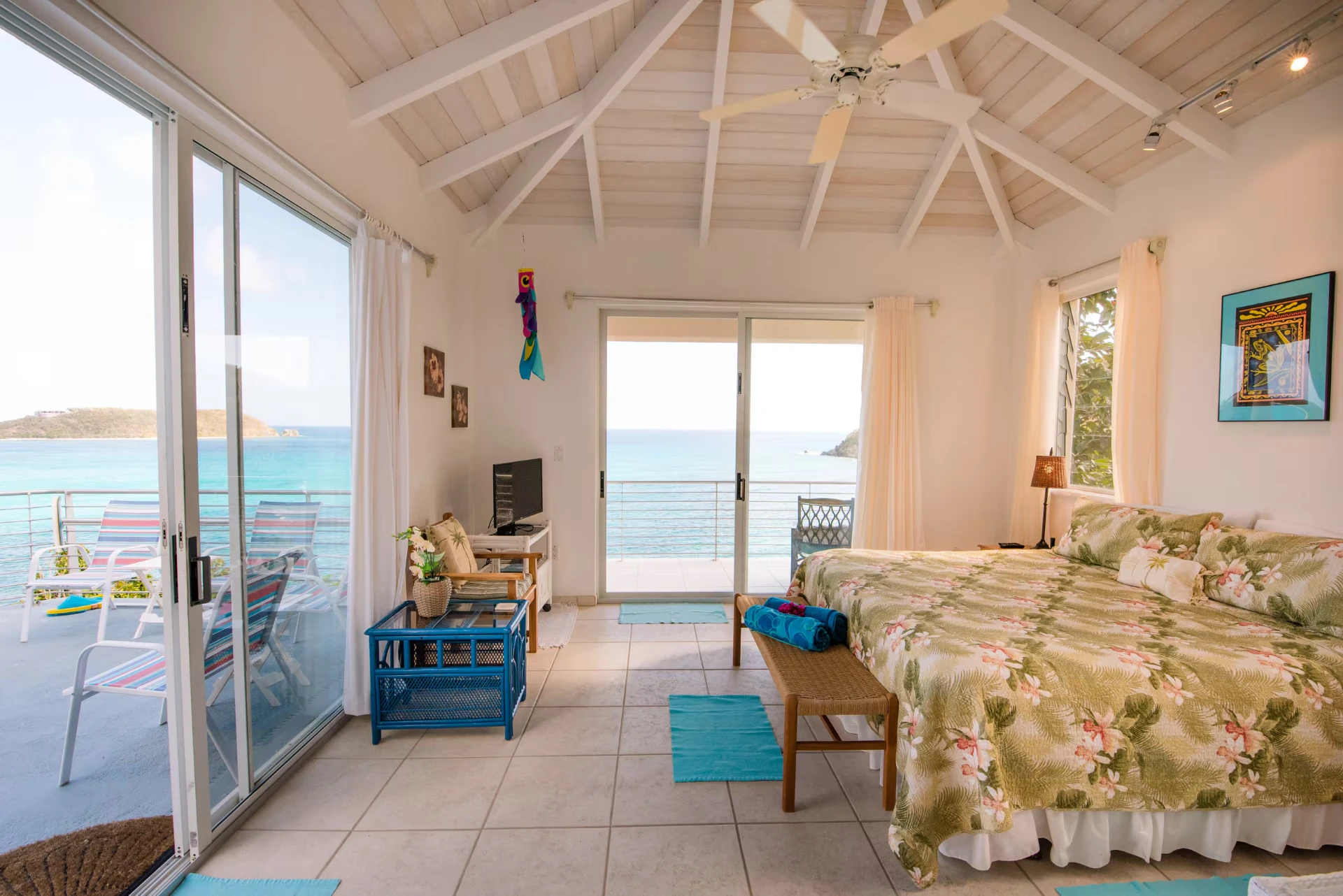 Upper guest suite looking out through walls of glass to the turquoise water and balcony seating